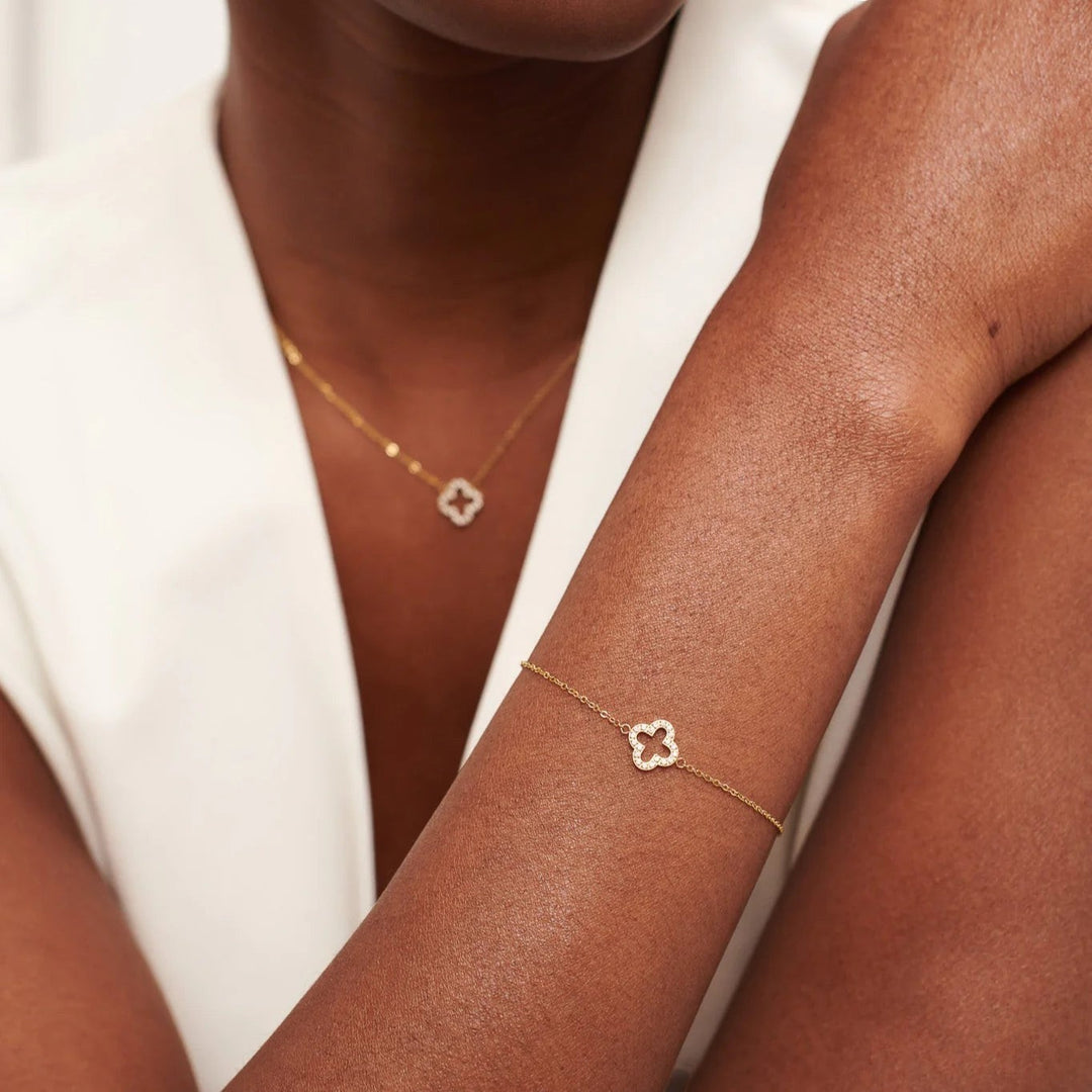 Niche Jewellery D.Louise gold pavé clover charm bracelet on a woman's wrist, featuring a delicate chain and sparkling detail.