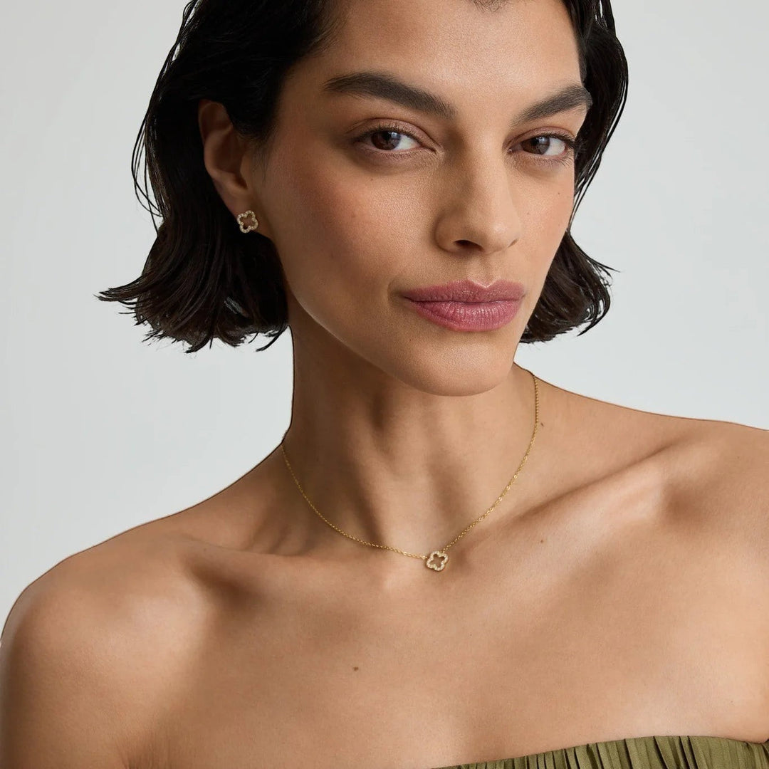 Niche Jewellery D.Louise gold pavé clover pendant necklace worn by a model with matching clover stud earrings