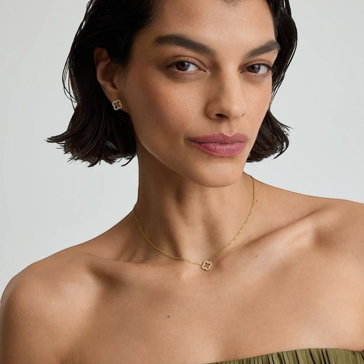 Niche Jewellery D.Louise gold pavé clover pendant necklace worn by a model with matching clover stud earrings
