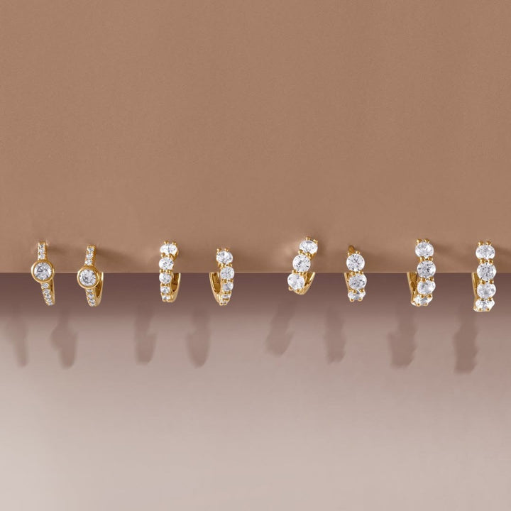 Niche Jewellery Ania Haie gold huggie hoop earrings featuring pavé cubic zirconia and bezel-set stones.