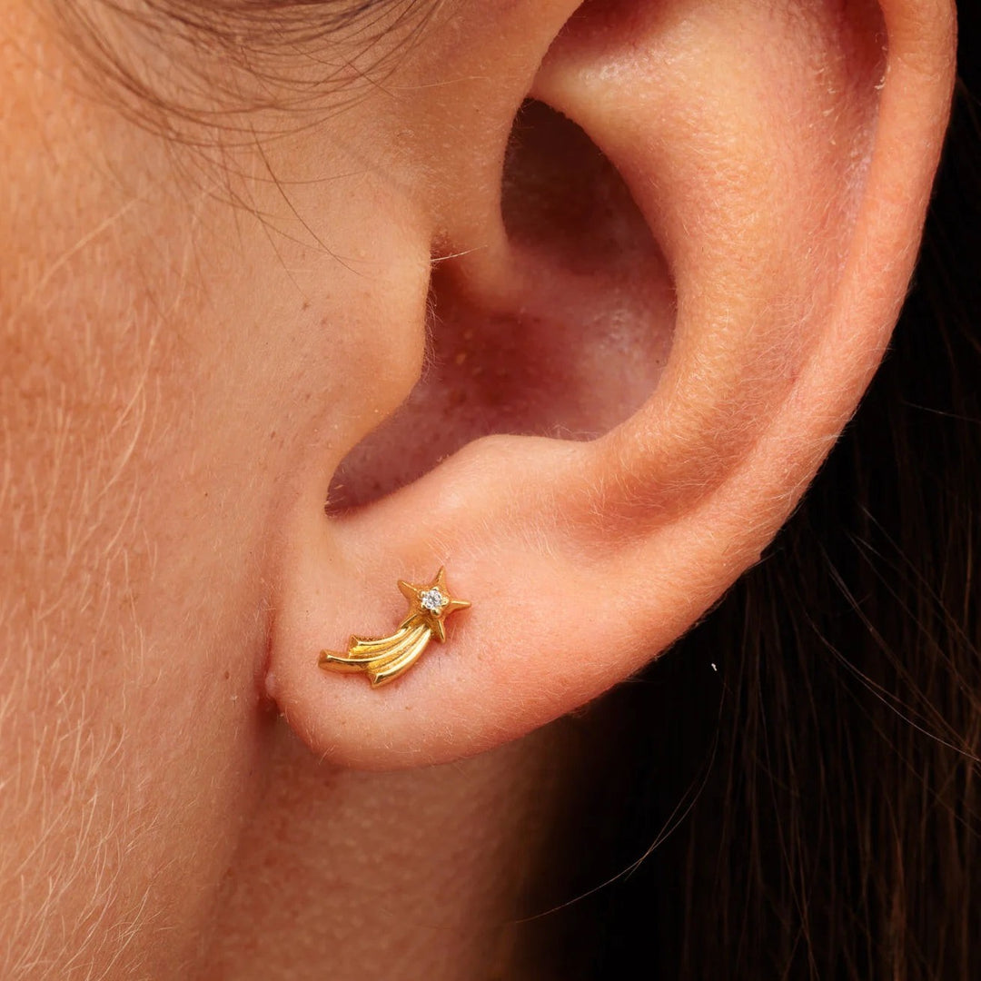 Niche Jewellery Scream Pretty gold shooting star helix earring with a sparkling stone, worn on a human ear.