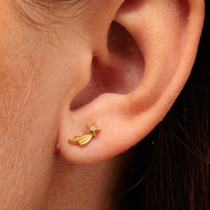 Niche Jewellery Scream Pretty gold shooting star helix earring with a sparkling stone, worn on a human ear.