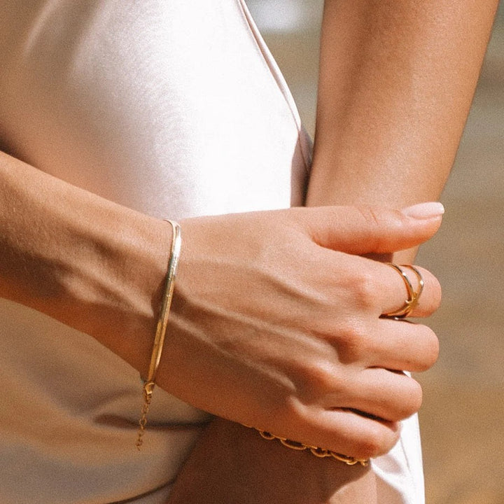 Niche Jewellery gold flat snake chain bracelet worn on a wrist with a delicate clasp detail