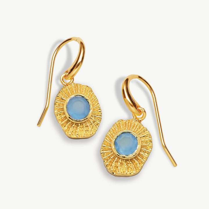 Niche Jewellery Sarah Alexander gold talisman drop earrings featuring blue gemstone centers and textured sunburst edges.