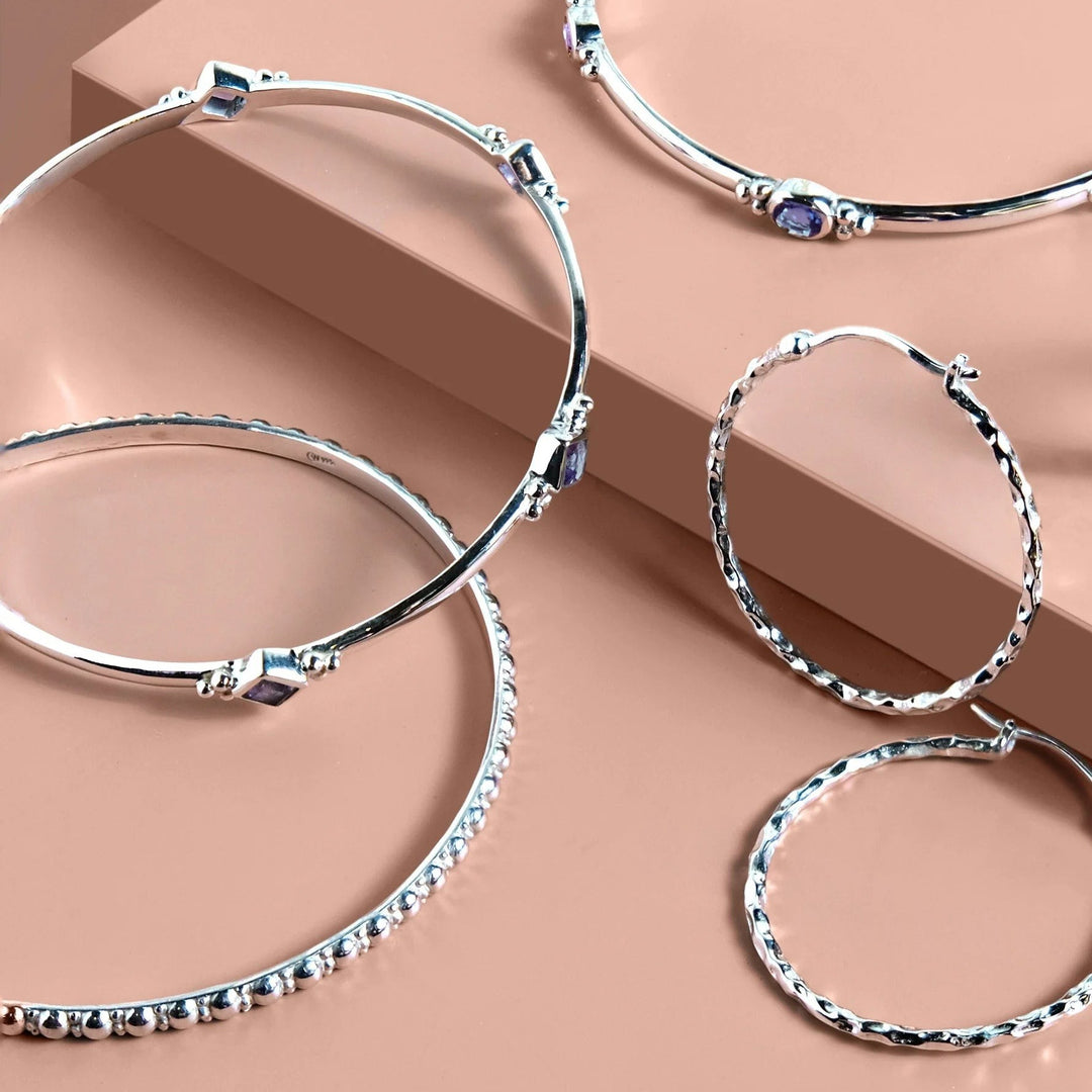 Niche Jewellery Charlotte's Web Jodhpur hammered sterling silver hoop earrings with textured finish on pink display.