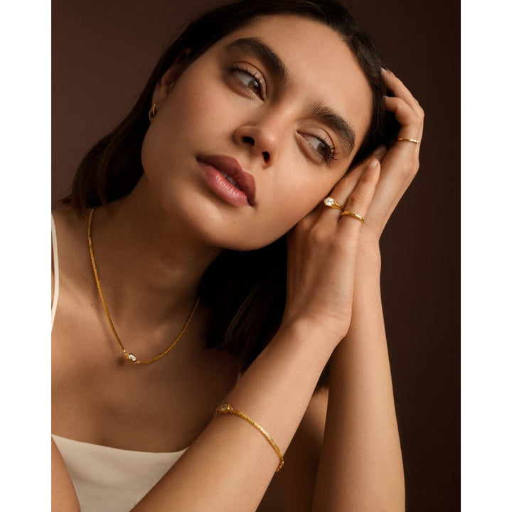 Niche Jewellery Katie Loxton Harlequin waterproof gold necklace worn by a model with matching bracelet and rings.