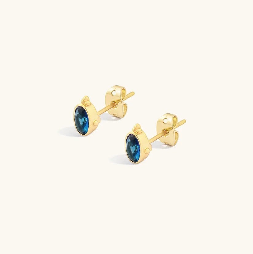 Niche Jewellery Indus sapphire stud earrings in 18k gold plated sterling silver with oval blue stones.