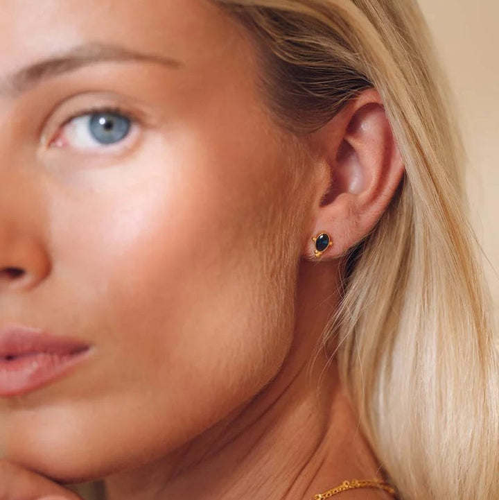 Niche Jewellery Indus sapphire stud earrings in 18k gold plated sterling silver worn by a woman