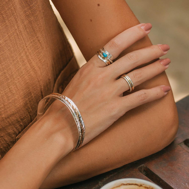 Niche Jewellery Charlotte's Web Karma Fortune unisex spinning ring in mixed recycled metals worn on a woman's finger.