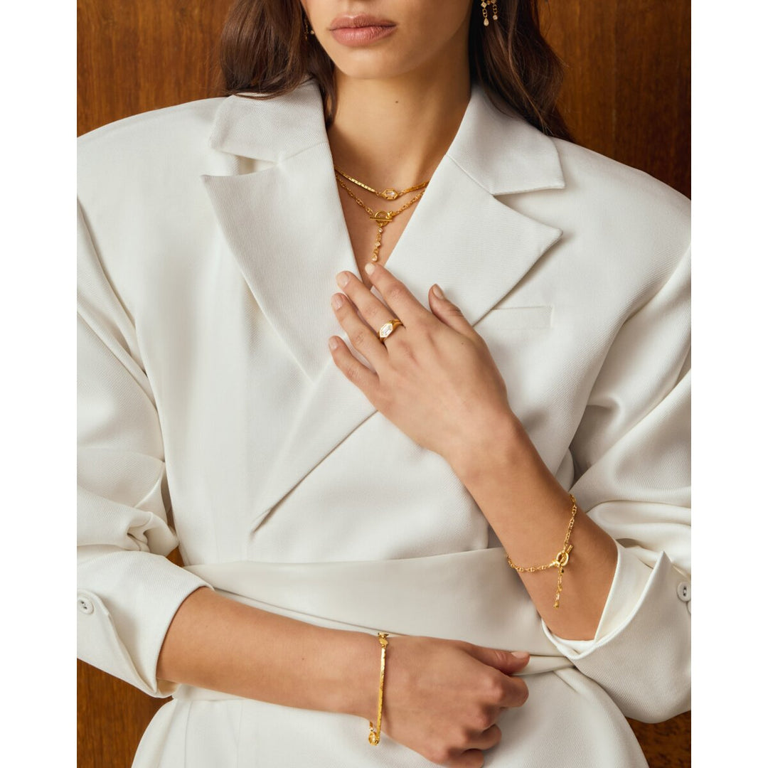 Niche Jewellery Katie Loxton waterproof gold chain bracelets worn by a woman in a white blazer