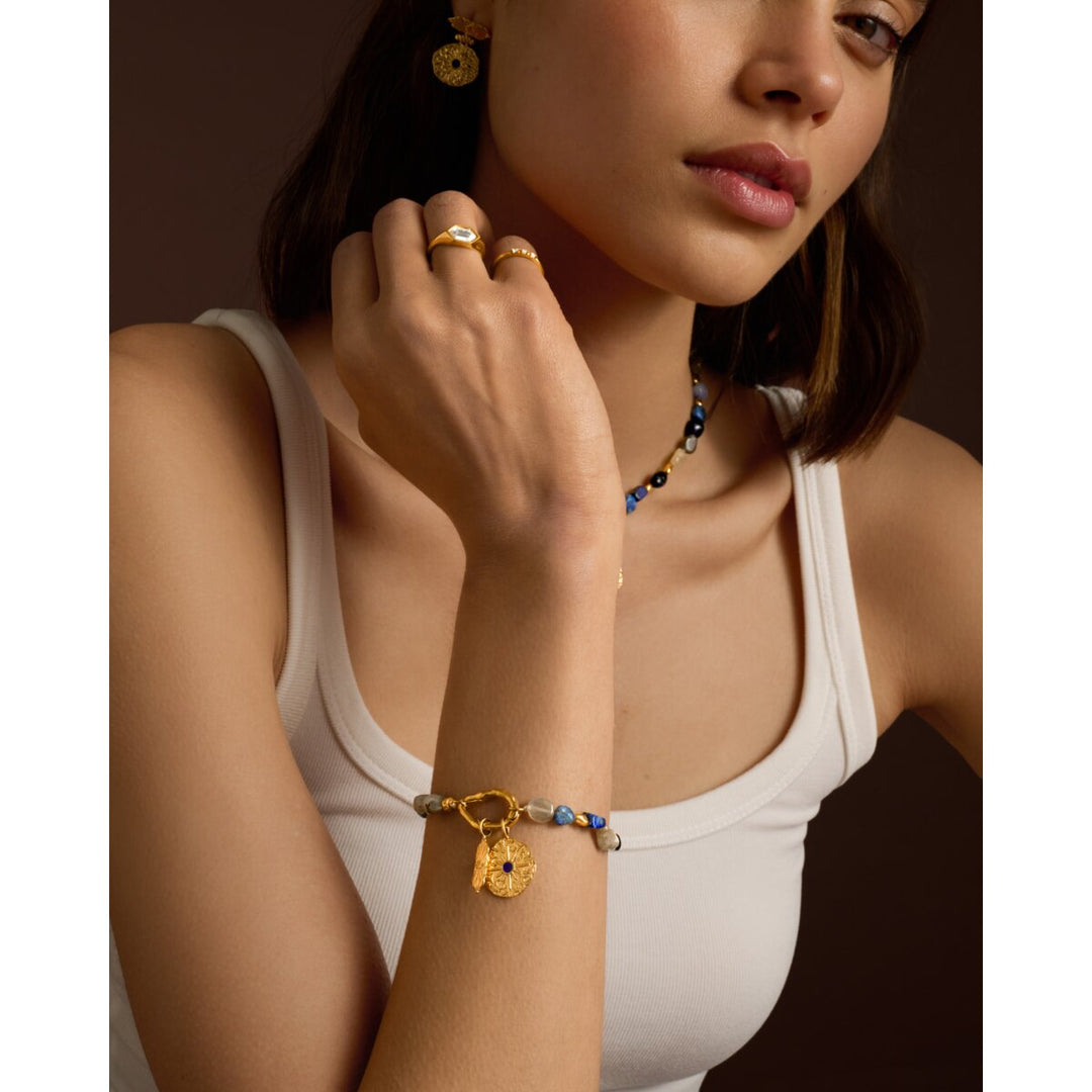Niche Jewellery Katie Loxton gold bracelet with navy semi-precious stones and a textured coin charm on a model