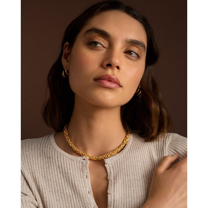 Niche Jewellery Katie Loxton Heritage chunky gold Byzantine chain necklace worn by a woman in a ribbed top