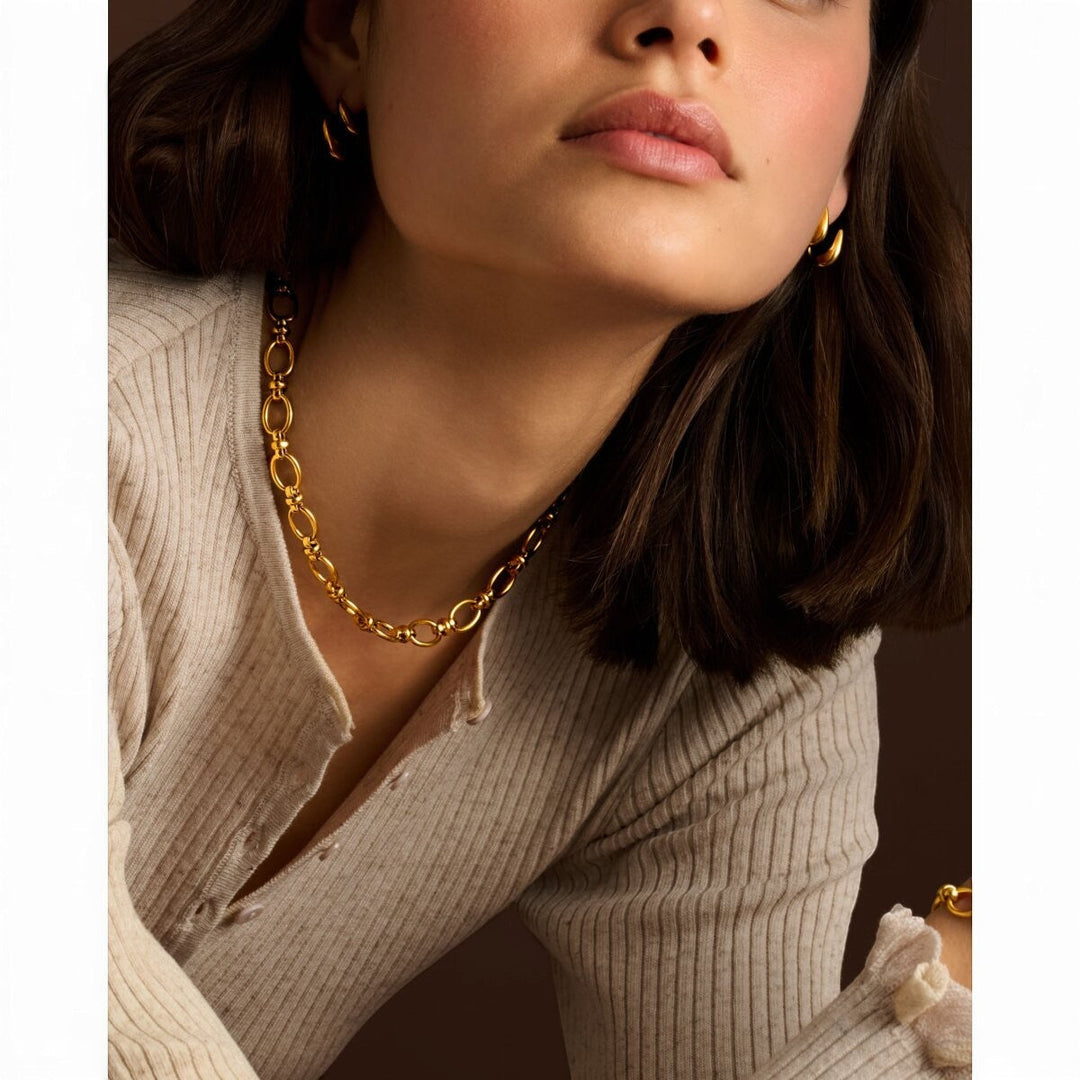 Model wearing Niche Jewellery Katie Loxton Empire waterproof gold chain necklace with matching gold hoop earrings.