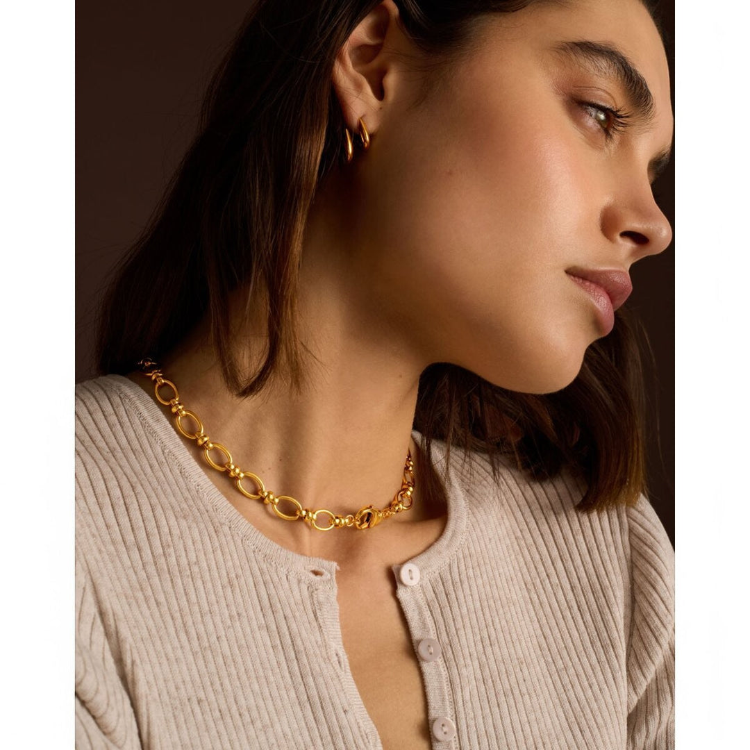 Niche Jewellery Katie Loxton Empire waterproof gold chain necklace worn by a woman in a beige ribbed cardigan