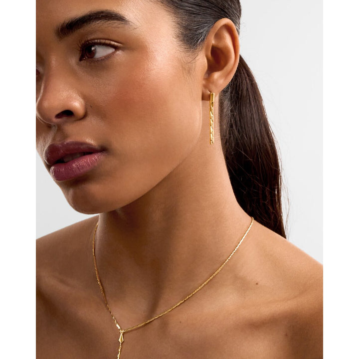 Niche Jewellery Katie Loxton gold drop stud earrings featuring a diamond-check pattern worn by a model