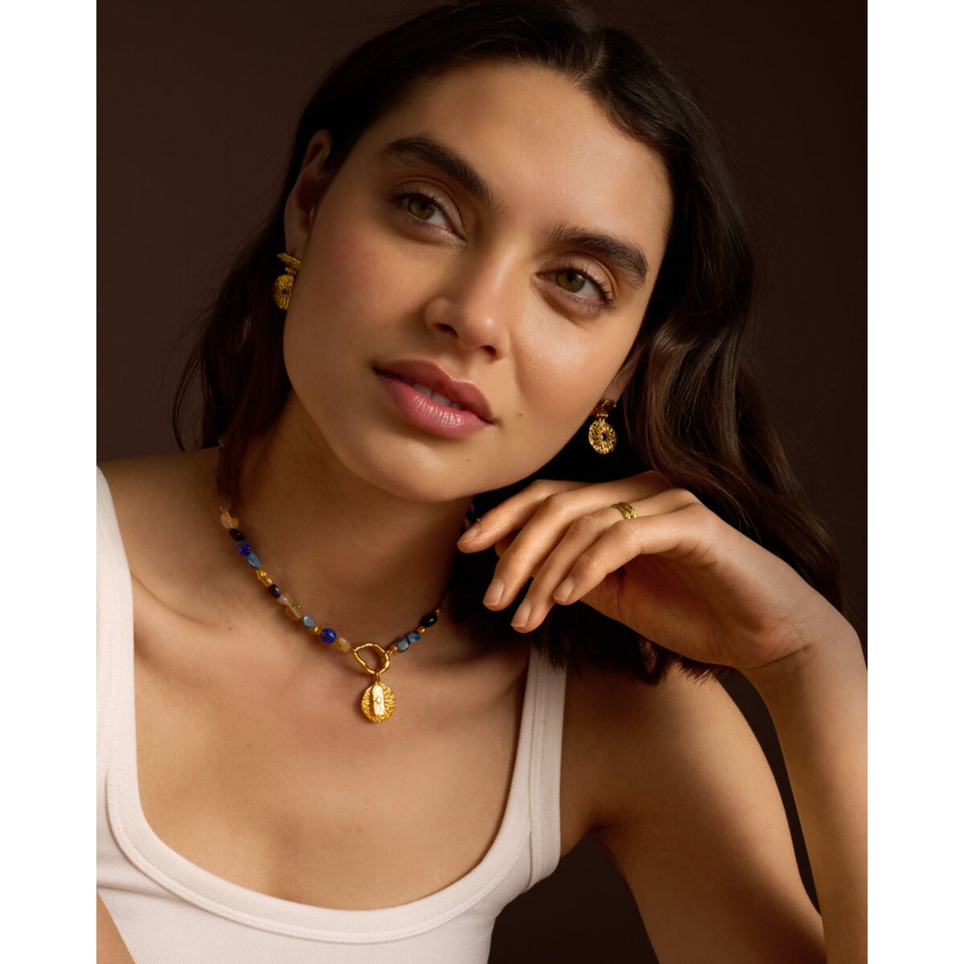 Niche Jewellery Katie Loxton Midnight Solesi gold earrings with dark stones worn by a woman in a white tank top