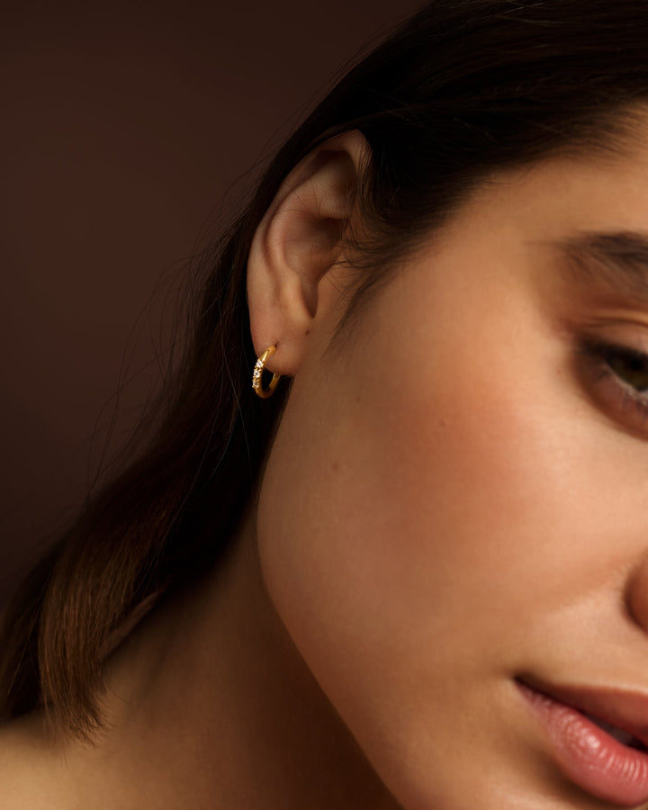 Niche Jewellery Katie Loxton Lumira waterproof gold hoop earring worn on a model's ear