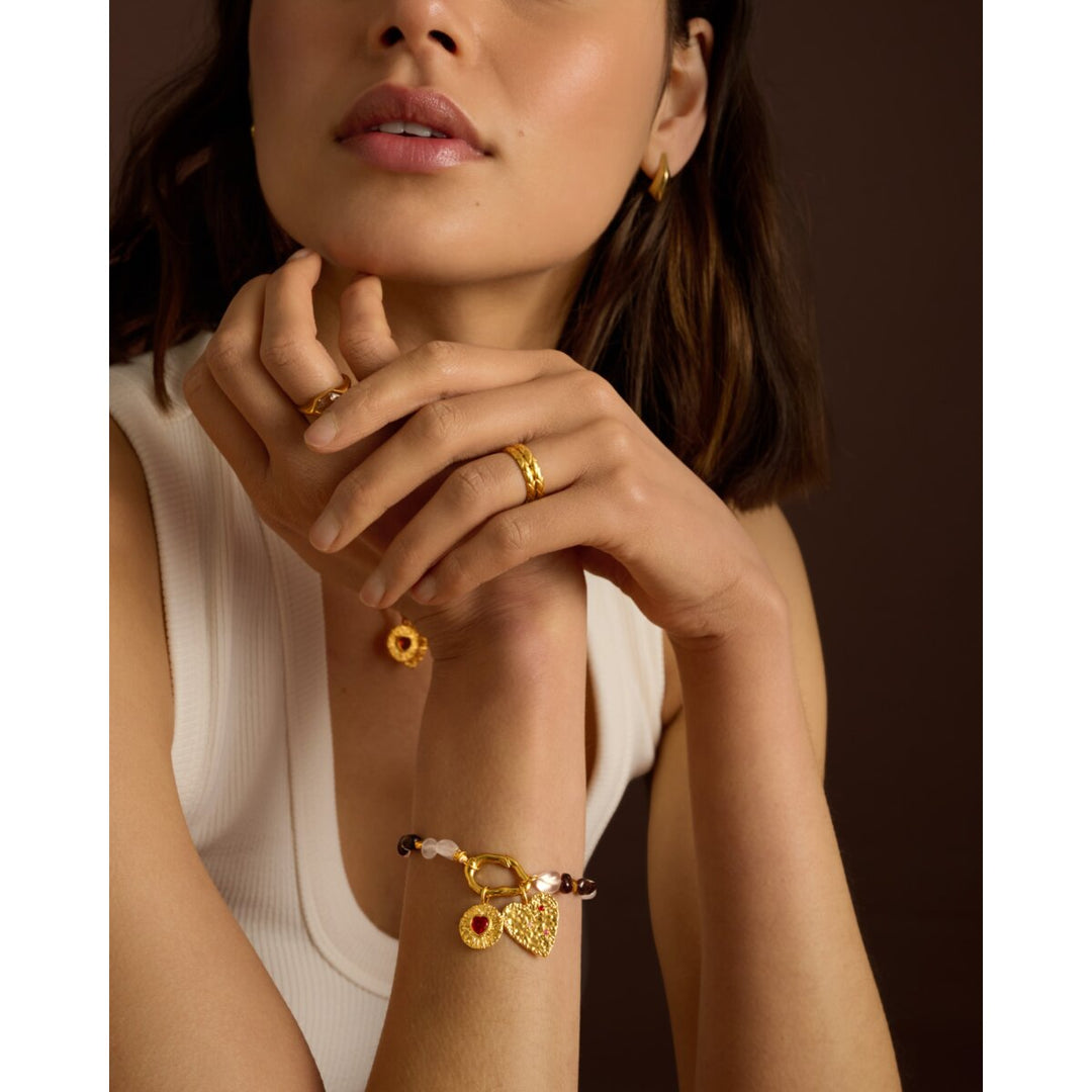 Niche Jewellery Katie Loxton gold chain bracelet with pink stones and heart charms worn on a model's wrist