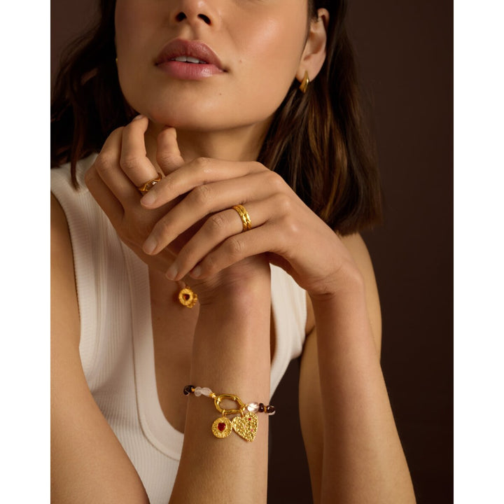 Niche Jewellery Katie Loxton gold chain bracelet with pink stones and heart charms worn on a model's wrist