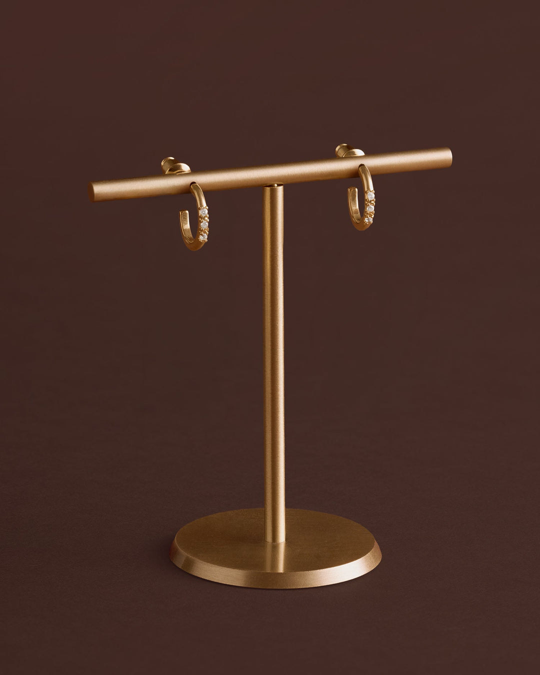 Niche Jewellery Katie Loxton Lumira waterproof gold hoop earrings with small crystal accents on a gold display stand.