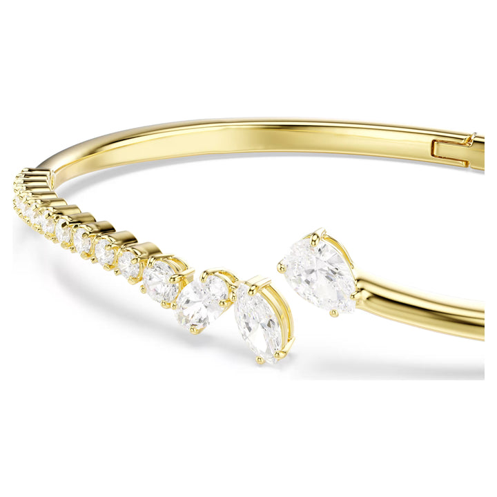 Niche Jewellery Swarovski Mesmera bangle featuring mixed cut white zirconia stones set in an 18k gold finish band.