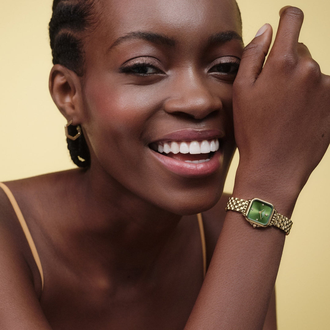 Niche Jewellery Olivia Burton Mini Grosvenor watch with a deep green dial and gold-tone bracelet on a smiling model