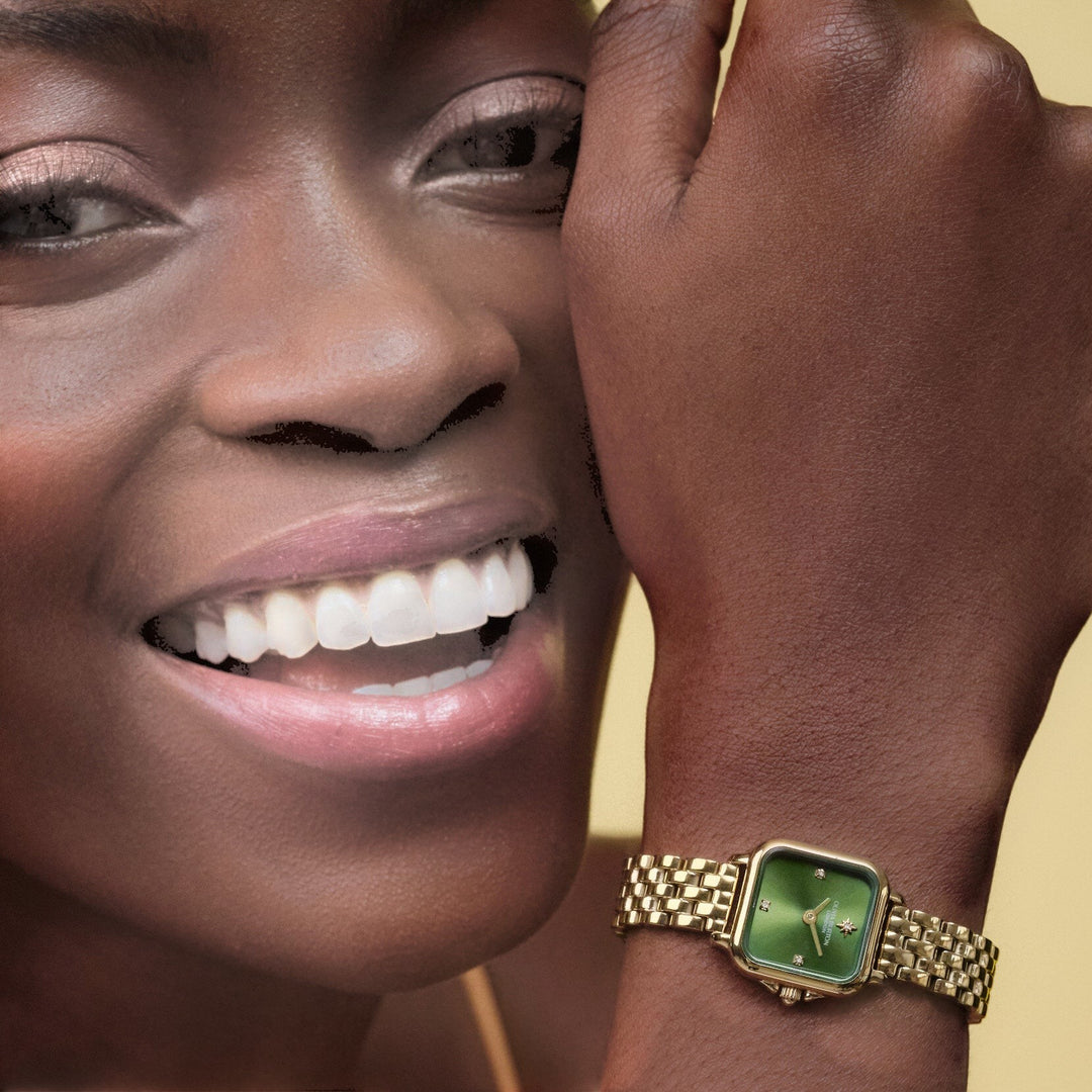 Niche Jewellery Olivia Burton Mini Grosvenor watch with a deep green dial and gold-tone bracelet on a smiling model