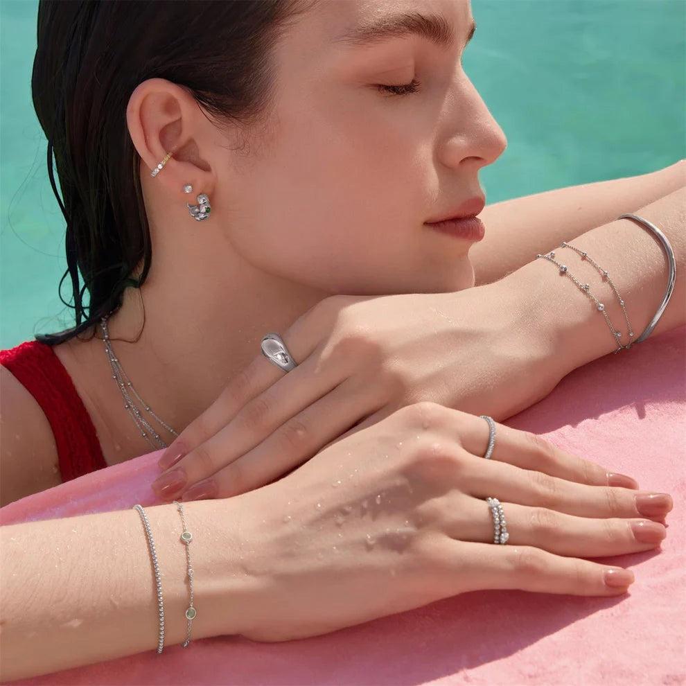 Niche Jewellery Ania Haie mint green station bracelet in sterling silver worn by a woman poolside
