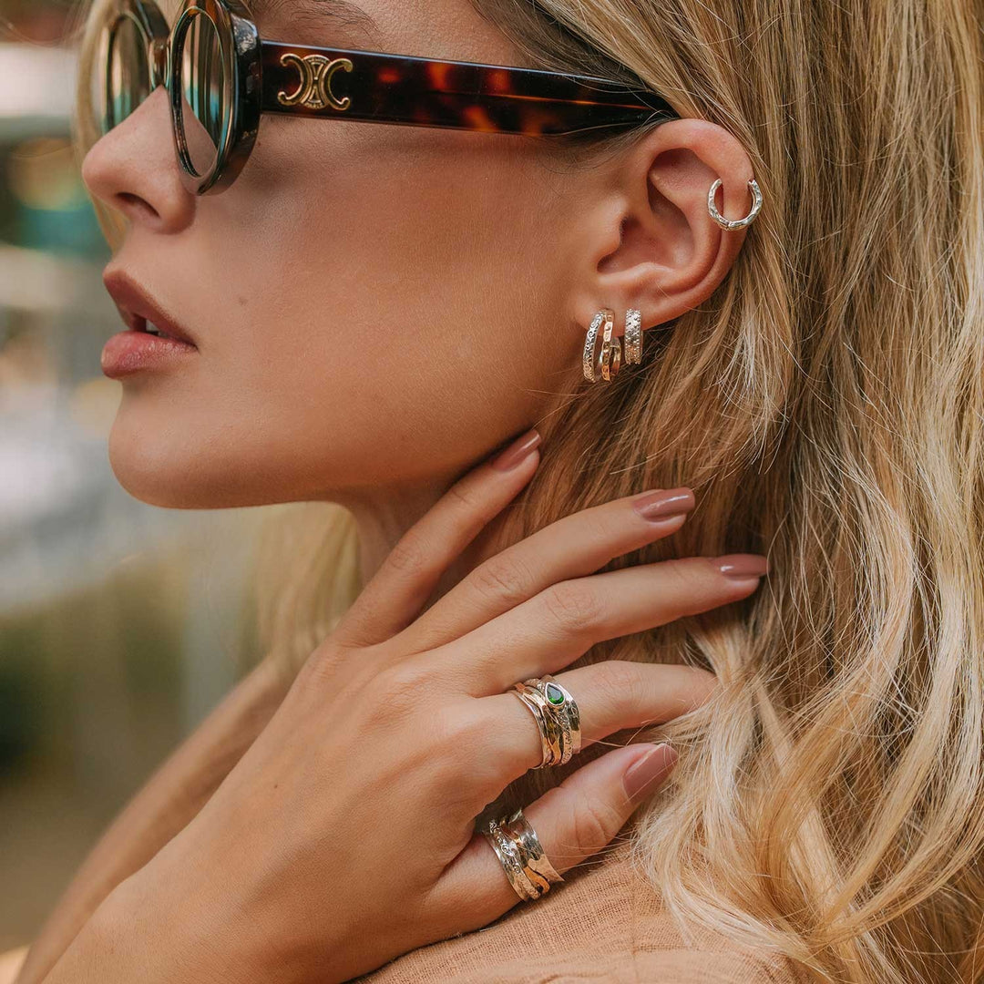 Niche Jewellery Charlotte's Web Aura Magic mixed metal double hoop earrings in silver and bronze with floral motifs worn by a woman.