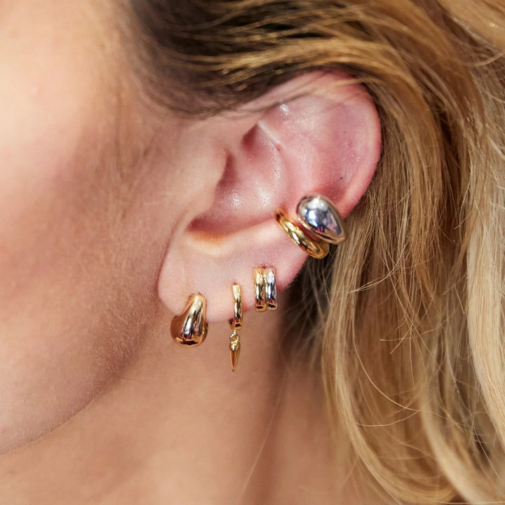 Niche Jewellery Scream Pretty mixed metal huggie earrings worn in a stacked ear piercing style.