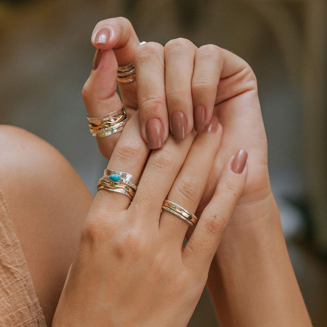 Niche Jewellery Charlotte's Web Karma Fortune mixed metal spinning rings worn on fingers with a turquoise accent