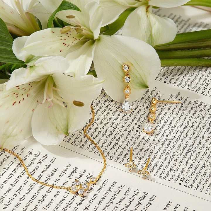 Niche Jewellery molten cascade teardrop stud earrings in silver, featuring bezel-set stones on a floral background.