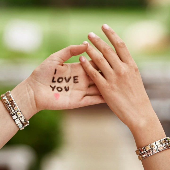 Niche Jewellery Nomination charm bracelet with black enamel heart on a woman's wrist with I Love You written on palm