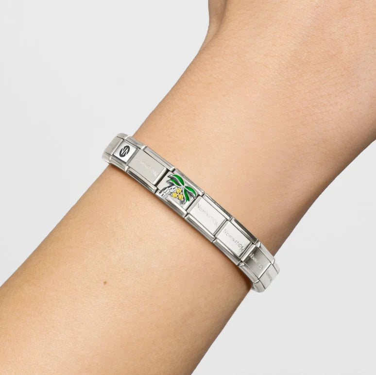 Niche Jewellery Nomination palm tree charm with green enamel and zirconia on a silver link bracelet worn on a wrist.