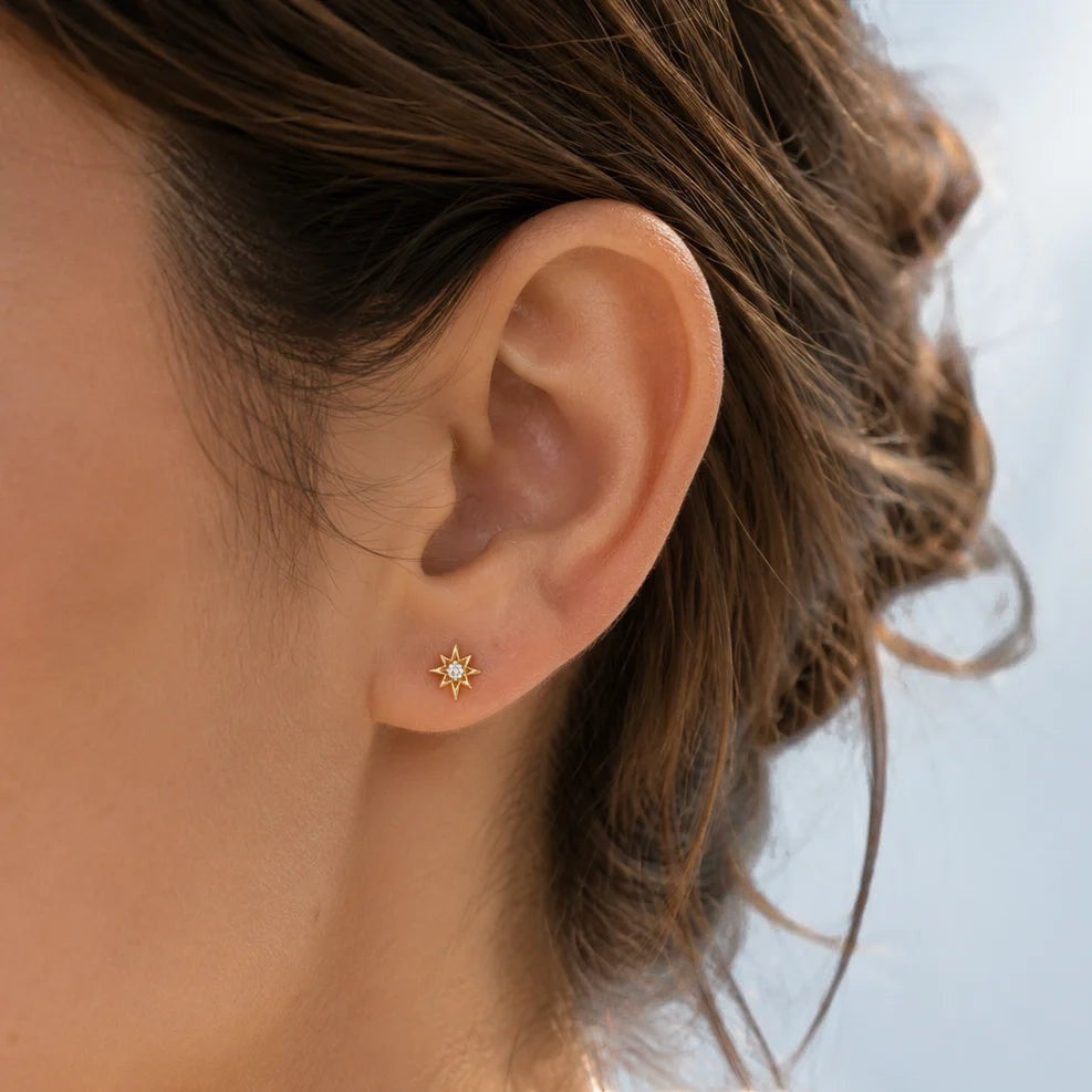Niche Jewellery gold stud earrings shaped like a north star with clear cubic zirconia.