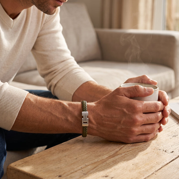 Niche Jewellery olive green braided nappa leather bracelet with stainless steel clasp on a man holding a coffee mug