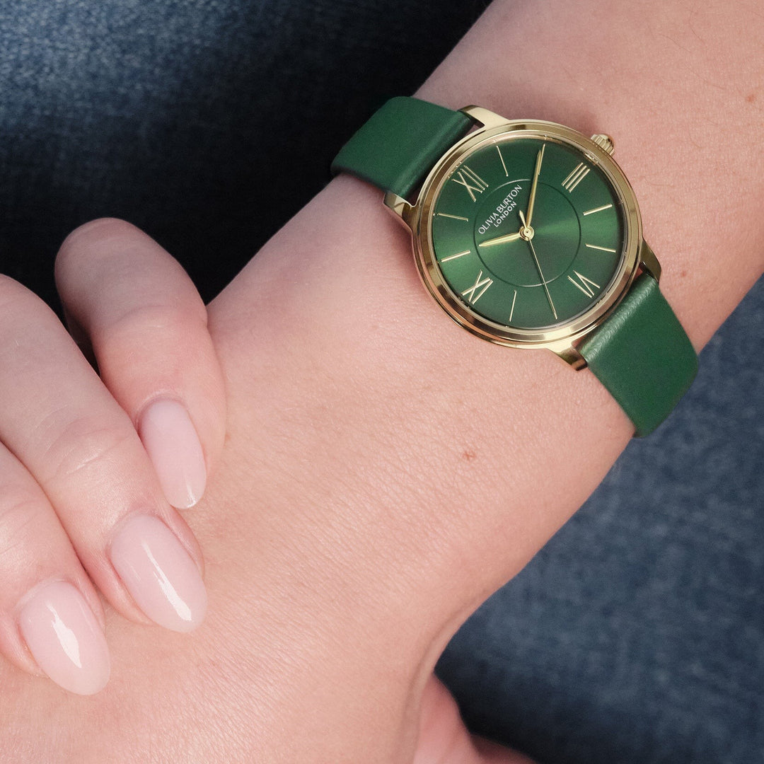 Niche Jewellery Olivia Burton Westbourne watch featuring a gold-tone case and deep green leather strap on a wrist.
