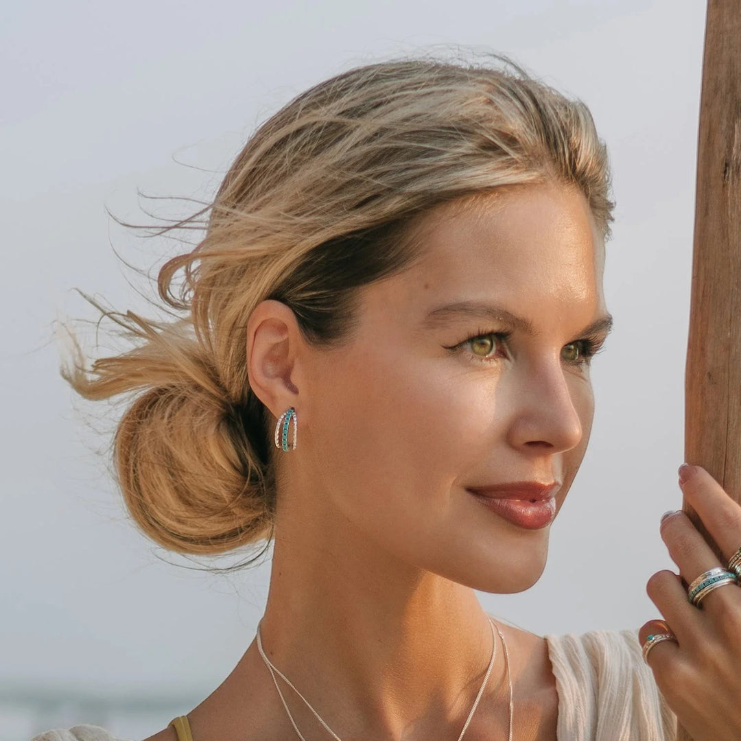 Niche Jewellery Charlotte's Web Parvati sterling silver hoop earrings with turquoise stones worn by a woman.