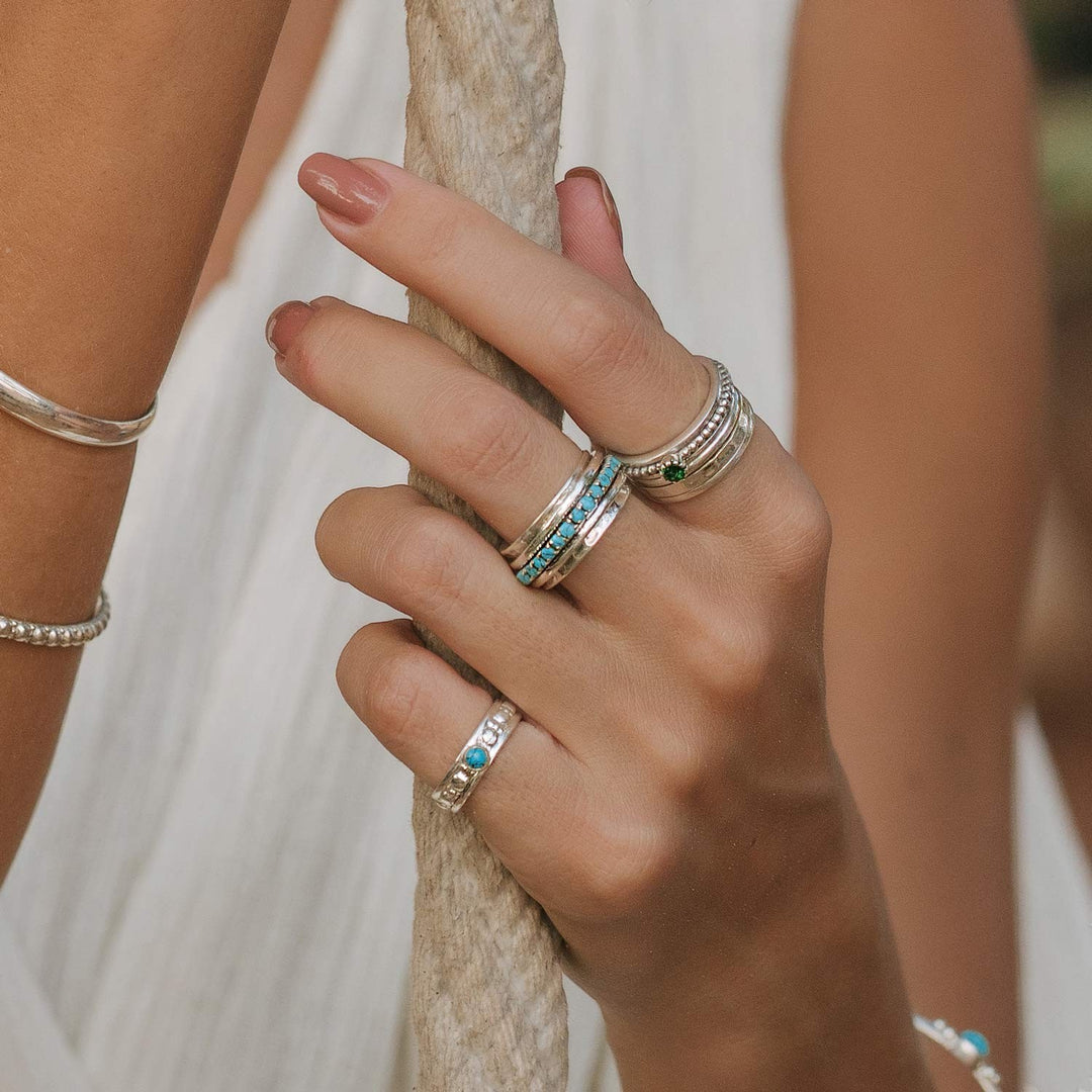 Niche Jewellery Parvati spinning ring in recycled sterling silver with turquoise inlay worn on a woman's hand.
