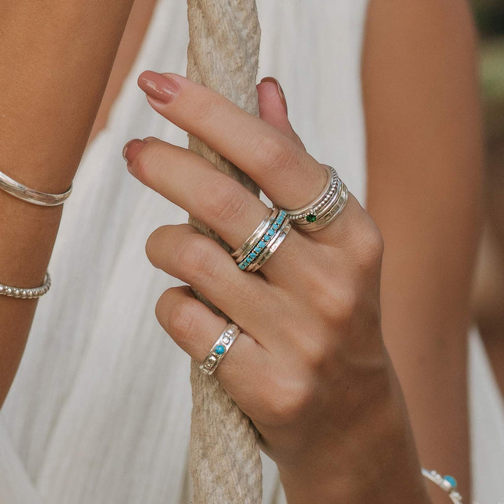 Niche Jewellery Parvati spinning ring in recycled sterling silver with turquoise inlay worn on a woman's hand.