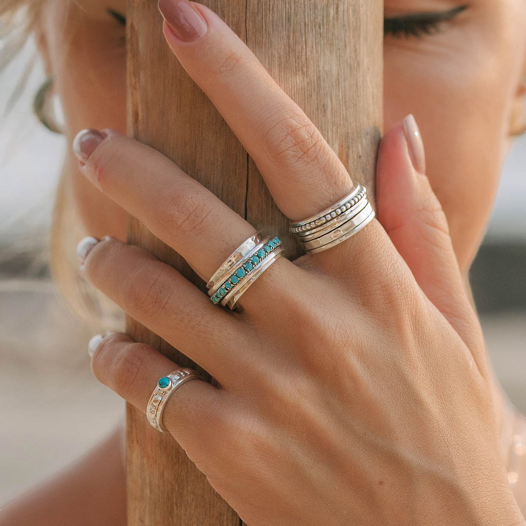 Niche Jewellery Charlotte's Web Parvati spinning ring in recycled sterling silver with turquoise inlay worn on a woman's hand.