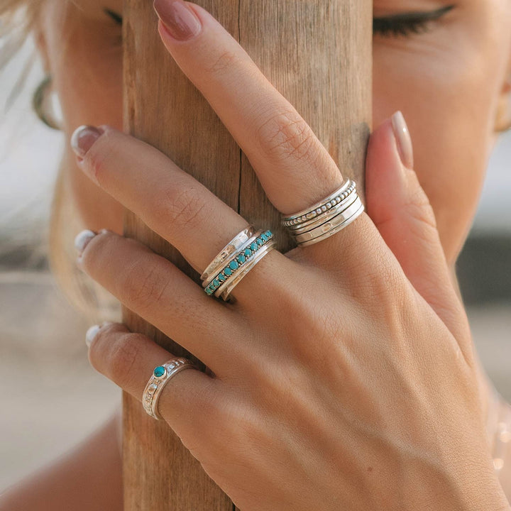 Niche Jewellery Charlotte's Web Parvati spinning ring in recycled sterling silver with turquoise inlay worn on a woman's hand.