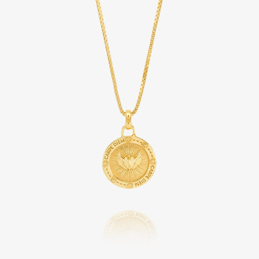 Niche Jewellery Rachel Jackson gold Carpe Diem token necklace featuring a heart, angel wings, and hands motif.