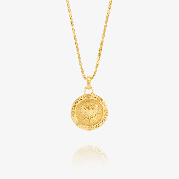 Niche Jewellery Rachel Jackson gold Carpe Diem token necklace featuring a heart, angel wings, and hands motif.