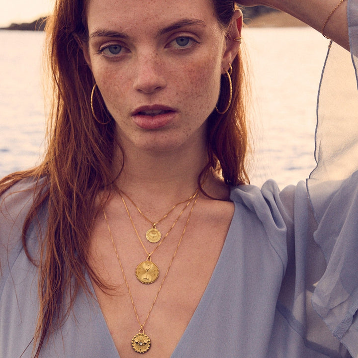 Niche Jewellery Rachel Jackson gold Carpe Diem necklace set featuring heart, hand, and wing motifs on a model