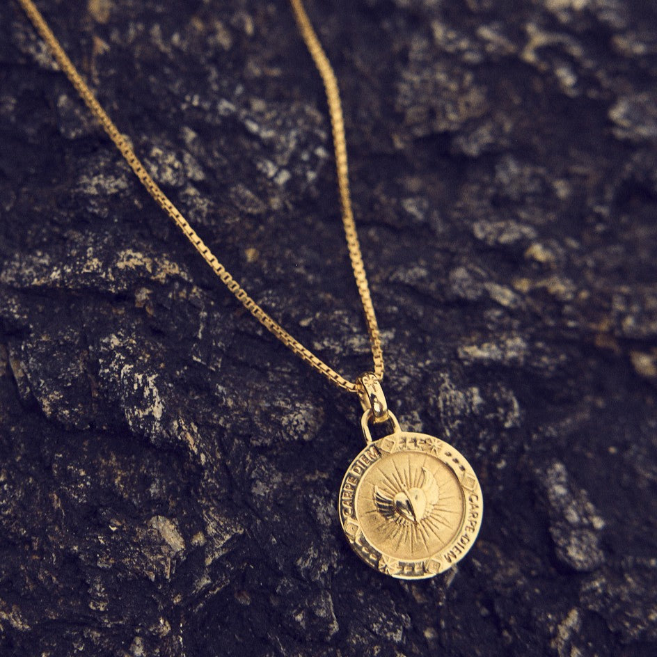 Niche Jewellery Rachel Jackson gold Carpe Diem necklace featuring a round pendant with heart and wing engravings.