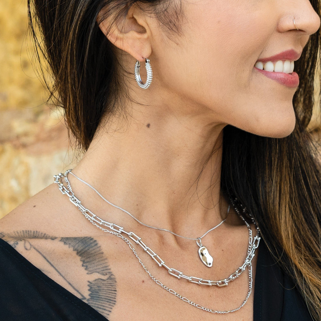 Niche Jewellery Sarah Alexander Sedona rhodium-plated silver bobble hoop earrings worn by a smiling woman