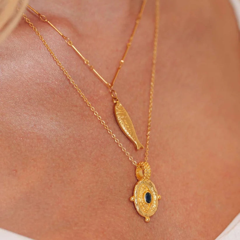 Niche Jewellery Formation Co Selkie fish pendant necklace in gold layered with a blue stone charm on a model