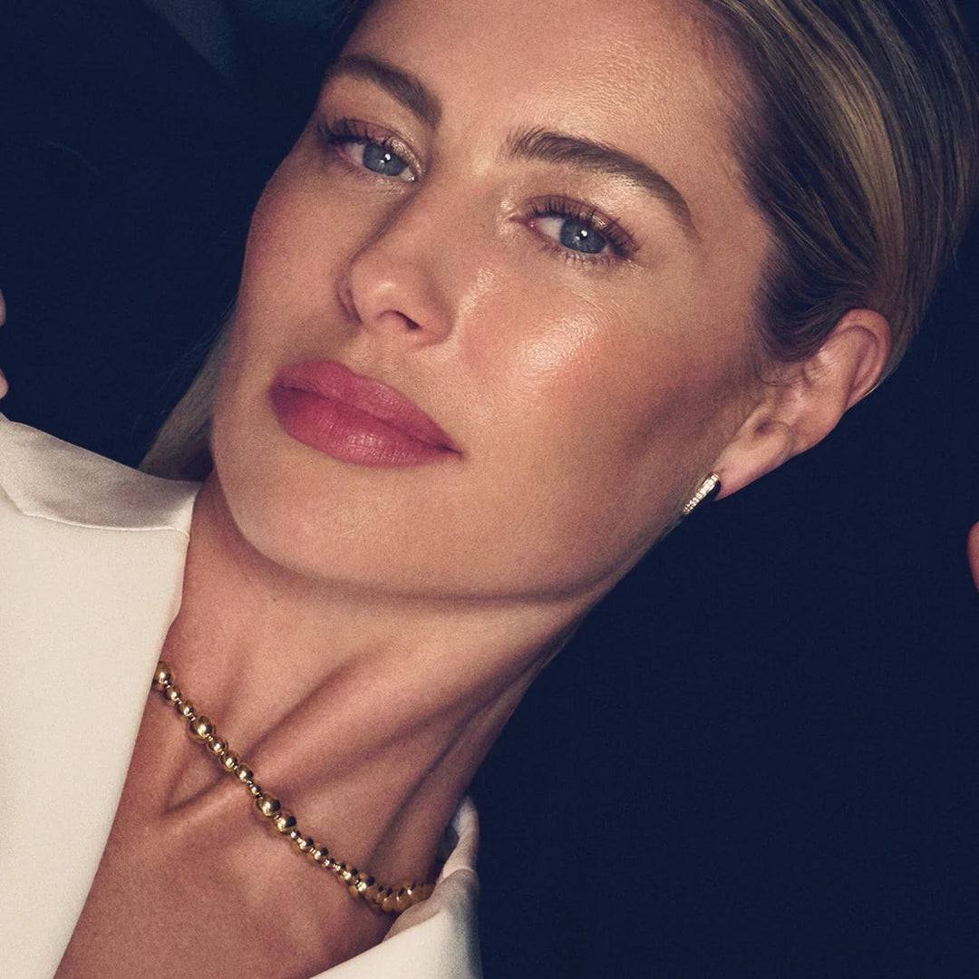 Model wearing a Niche Jewellery Sif Jakobs Bormio gold-plated beaded necklace against a dark background.