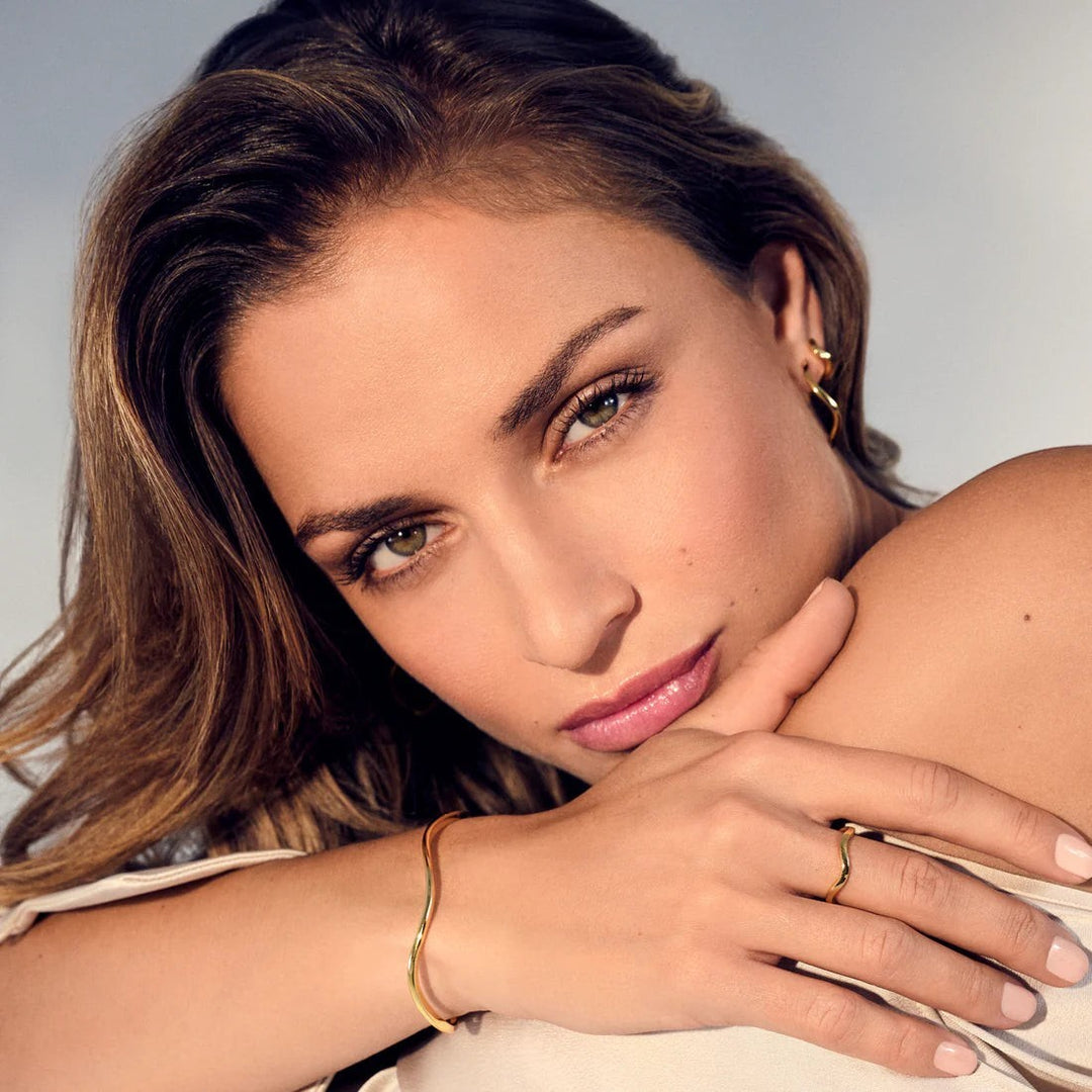 Model wearing Niche Jewellery Sif Jakobs Ellera Waves gold-plated sterling silver ring with a polished wave design.
